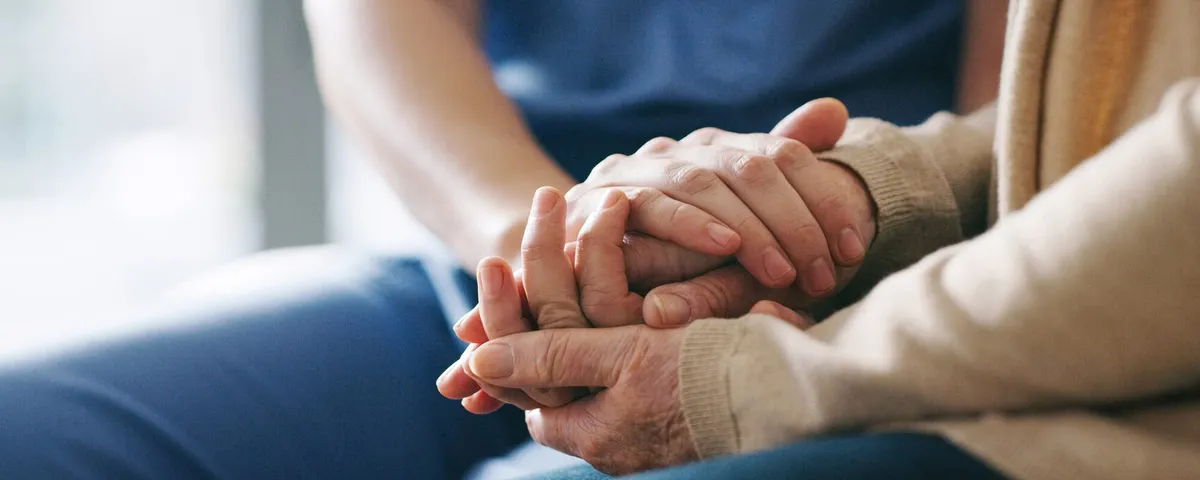 A SYNERGY HomeCare caregiver gently holding an elderly client's hands — continuous around-the-clock care