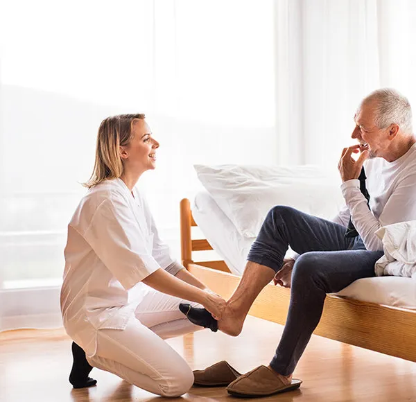 A SYNERGY HomeCare caregiver carefully helping a senior navigate steps safely at home