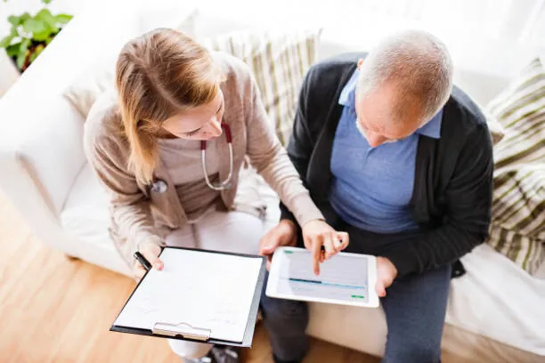 A SYNERGY HomeCare caregiver reviewing paperwork with a senior at a table while talking through the cost of a home care plan
