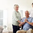 A SYNERGY HomeCare caregiver with a senior couple in a bright living room