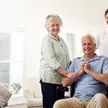 A SYNERGY HomeCare caregiver with a senior couple in a bright living room