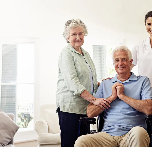 A SYNERGY HomeCare caregiver with a senior couple in a bright living room