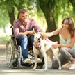 A caregiver embracing a senior couple, one of whom uses a wheelchair, in a warm home setting